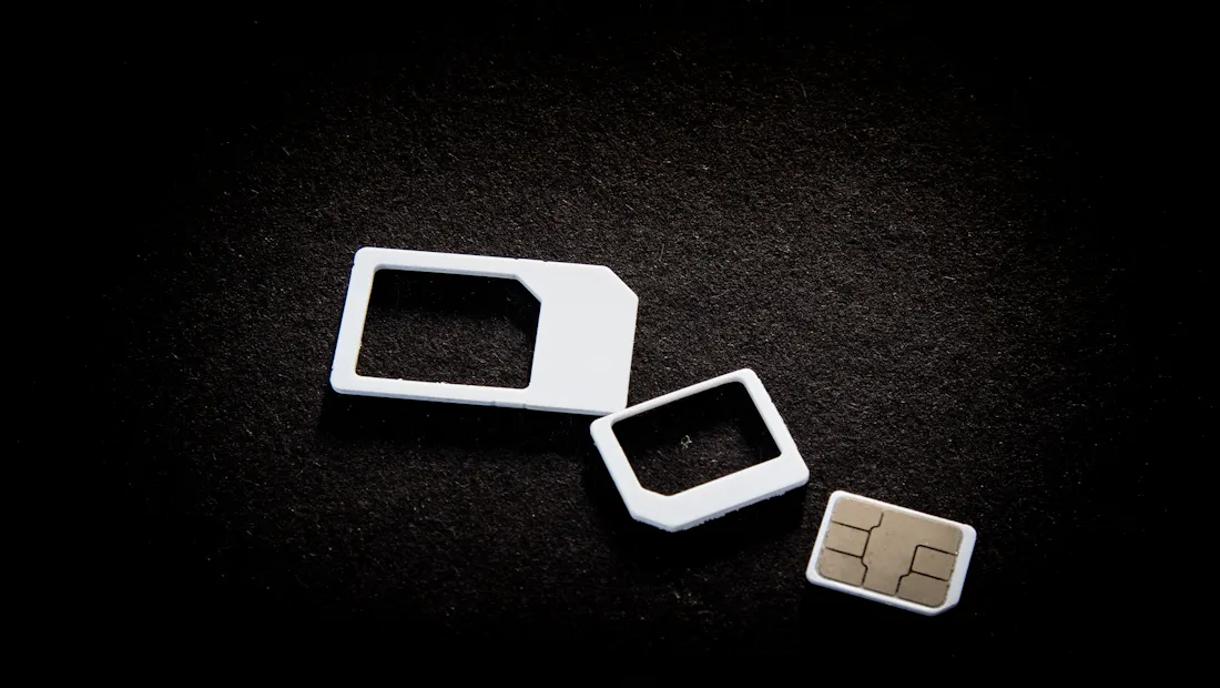 A SIM card and its adaptors on a dark surface