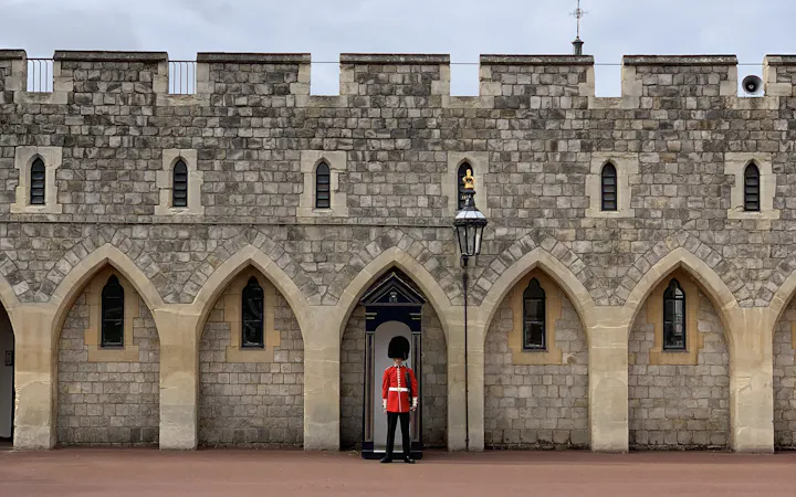 A guardsman in a red tunic and bearskin on sentry duty outside Windsor Castle