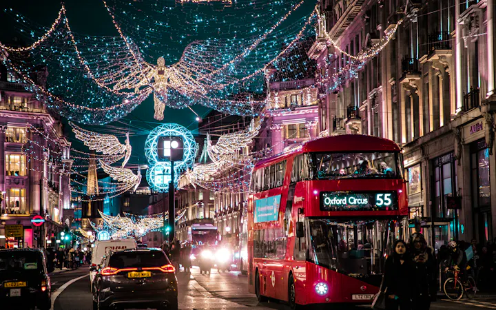 A red London bus passing under Christmas lights on a busy shopping street